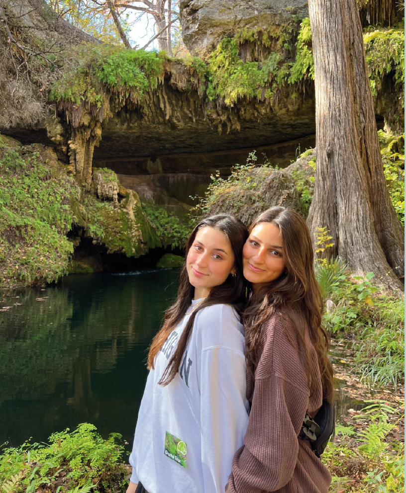 Two young women, Fionna and Shannon Noori standing by a small river in the woods.