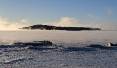 Picture of Gichi-Onigamiminis (Grand Portage Island) surrounded by the icy winter waves of Gichi-gaaming (Lake Superior) taken by Rick Novitsky.